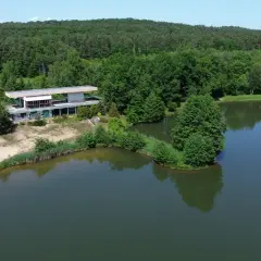 Nowoczesny budynek nad jeziorem, otoczony lasem. Zalew Skowronek w letniej scenerii.