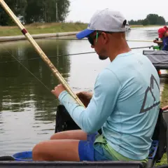 Wędkarz trzymający tyczkę, gotowy do łowienia ryb na kanale.