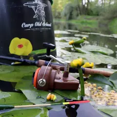 Wędka, kołowrotek, spławik i przynęta na tle kwitnących lilii wodnych.