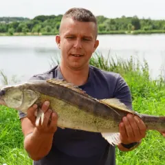 Szczęśliwy wędkarz prezentuje okazałego sandacza złowionego nad zalewem Brody.