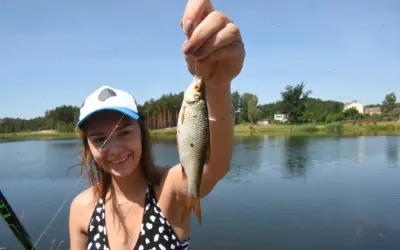 Uśmiechnięta wędkarz z rybą na haku nad zalewem przeczycko-siewierskim.