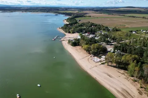 Widok z lotu ptaka na Zalew Mietkowski z piaszczystą plażą, mariną z łodziami i zielonymi terenami rekreacyjnymi.
