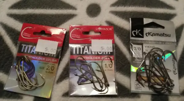 Trzy opakowania haczyków wędkarskich. Dwa z napisem "TITANIUM", jeden z napisem "Kamatsu". Jaki haczyk na lina wybrać?